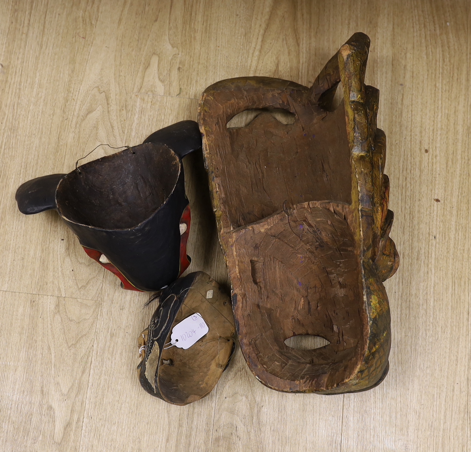 A Ceylonese painted wood mask, an East Java mask and a pig mask, largest 50cm long